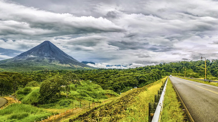 Eine Landstraße in Costa Rica. Im Hintergrund die Kulisse des Vulkan Arenal.
